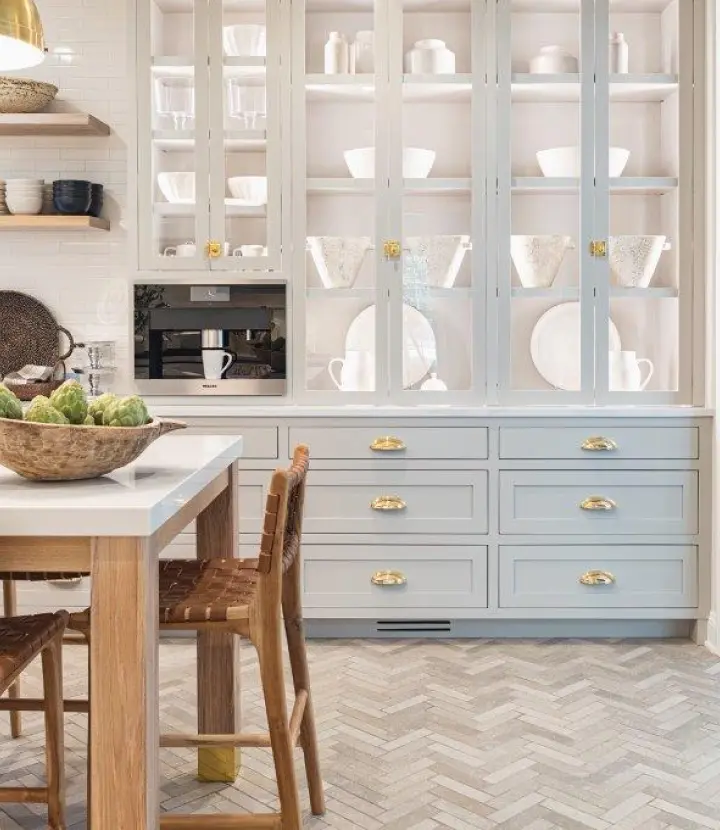 A kitchen with white cabinets and wooden floors.