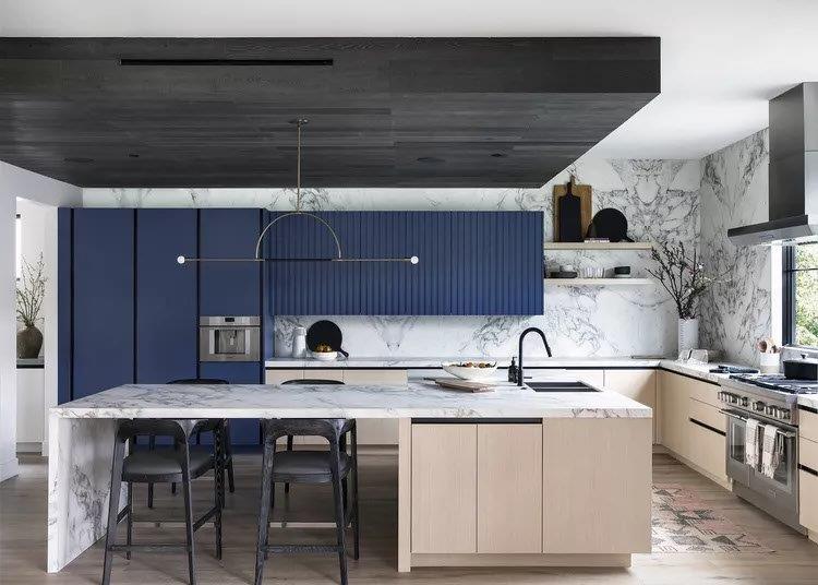 A kitchen with blue cabinets and black counter tops.